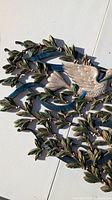 Close-up of bird wing and surrounding leafy branches of the metal wall art.