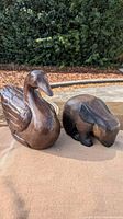 Pair of wooden animal figurines including swan and rabbit on outdoor cloth surface