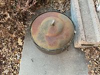 Top view of the copper hose pot showing its domed lid with bird finial and surrounding dried leaves.