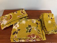 Set of folded tablecloth, 8 napkins, and carrying case displayed on wooden surface