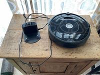 Top view of iRobot Roomba vacuum and charging dock on wooden surface.