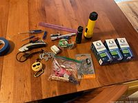 Photo showing the assortment of tools, flashlights, key chains, clips, and Brita water filters on a wooden table.