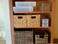 Shelving unit with assorted organizing bins including clear plastic containers and woven wicker baskets