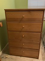 Front view of upright 5-drawer dresser in natural wood finish