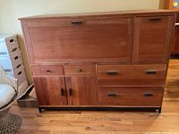 Front view of wood office storage cabinet showing drawers, doors, and drop-down compartment with black metal handles and lock.