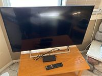 Front view of the Sony 42.5-inch TV placed on a wooden surface showing the screen and base stand.