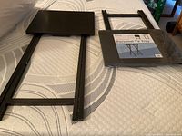 Two black personal TV trays, one unpackaged, one still wrapped in original packaging with label visible