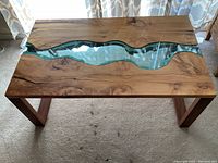 Top-down view of full tabletop showing wood grain and wave-shaped glass insert