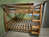 Side view showing twin top bunk and full bottom bunk with slatted frames and attached ladder