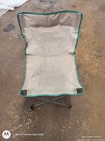 High back camping chair showing beige fabric seat and backrest with green trim, foldable metal frame.