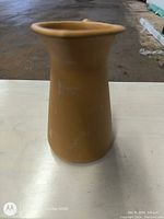 Front view of earth ceramic milk jug showing spout and smooth surface.