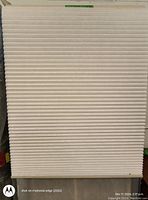 Photo of a neutral-colored cordless honeycomb cellular window shade, showing pleated design and fabric texture.