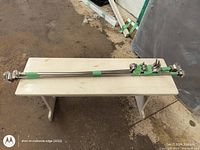 Four silver adjustable curtain rods taped together with mounting brackets on a bench in a workshop.