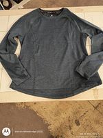 Front laid flat view of gray men's long sleeve active wear shirt from Spyder, showing fabric texture and style.