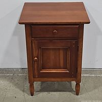 Front view of the wooden accent end table showing drawer and cabinet door closed.