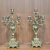 Pair of candelabras displayed side by side with enamel panels and ornate bases
