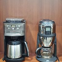 Cuisinart coffee maker and Innovations Fine T gourmet tea maker side by side on wooden surface.