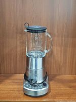 Full view of the Breville Fresh & Furious Blender assembled on a wooden surface with a glass pitcher and stainless steel base.