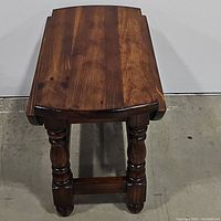 View of the drop leaf accent table with leaves down, showing turned legs and stretcher bar base.