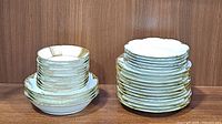 Photo showing stacked vintage gold trimmed dessert bowls and dinner plates with scalloped edges and gold trim.