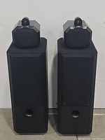 Front view of both black floor-standing speakers side by side