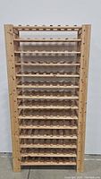 Front view of wooden wine rack showing 13 shelves designed for wine bottle storage.