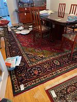 Red and navy wool rug under dining table, showing central field and border motifs