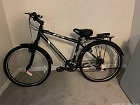 Side view of the black IronHorse Maverick commuter bicycle showing frame, seat, rear rack, and kickstand.