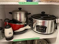 Shelved items including Hamilton Beach slow cooker, pots, foil pan, and Slap Chop chopper