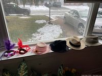 Wide shot of all items displayed on a window sill, showing hats and the feathered masks.