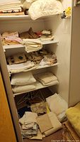Shelves filled with folded sheets, towels, and pillowcases stacked in piles of neutral colors