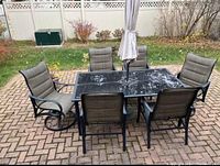 Overhead view of rectangular glass-top table with umbrella and all six chairs on patio without snow
