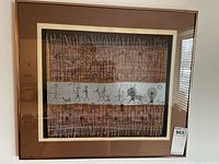 Framed signed and numbered art print hanging on a light-colored wall, showing full artwork and frame.