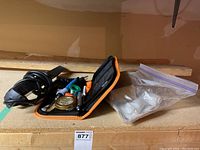 Soldering kit and hot glue gun items displayed on shelf including carrying case, wires, tools, and power strip.