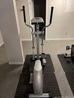 Front view of Proteus EEC 3005 step machine showing foot pedals, dual handlebars, and base with rubber mats beneath.