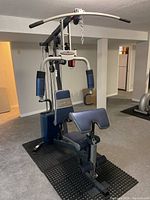 Front view of home gym including lat pulldown bar, chest press arms, and seating