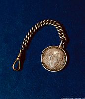 Obverse side of the silver coin pendant showing profile of Paul von Hindenburg and inscription around edge.