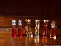 Six mini Givenchy perfume bottles arranged in a row on a wooden surface showing different styles and liquids.