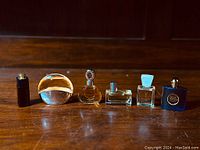 Photo showing all 6 mini designer perfume bottles arranged in a row on wooden surface.