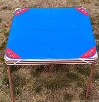 Top view of blue tablecloth secured on metal foldable table outdoors showing embroidered red corners