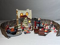 Full view of all ceramic Christmas tabletop figurines and decorations including the lighted ceramic house surrounded by wooden fence.