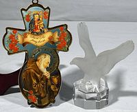Photo showing the front view of the St. Ro plastic wall ornament cross with colorful floral and saint imagery, alongside the frosted glass eagle figurine on its polished glass pedestal.