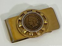 Front view of the gold-tone money clip showing the 1906 Indian Head cent embedded in the center with decorative details.