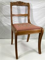 Full front view of the wooden chair showing curved legs, carved floral backrest, and needlepoint seat