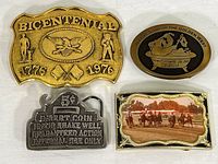 Four belt buckles shown together: Bicentennial, Native Sons of the Golden West, coin slot, and horse race scene buckle.