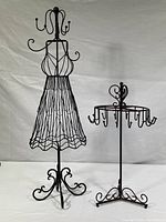 Both wire sculpture jewelry racks; taller dress form shape and smaller circular rotating stand shown together