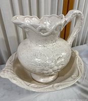 Ceramic pitcher and wash basin set together showing speckled off-white color and textured design