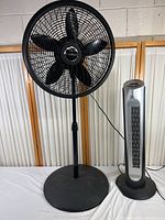 Full view of two floor fans, one tall Holmes fan and one shorter Lasko fan, showing physical condition and design.