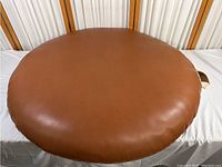 Top view of round faux brown leather floor pillow, showing smooth surface and circular shape.