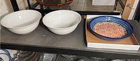 Two large white bowls and one colorful Polish pottery bowl on a shelf.